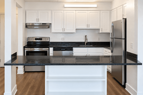 New Britain apartment for rent - A kitchen with white cabinets and a black countertop.