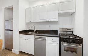 New York apartment for rent - A kitchen with white cabinets and black countertops.