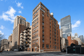 New York apartment for rent - A large red brick building is in the middle of a city street.