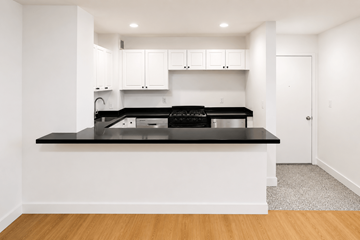 New York apartment for rent - A modern kitchen with white cabinets and black countertops.