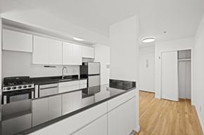 New York apartment for rent - A modern kitchen with white cabinets and black countertops.