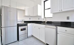 New York triplex for rent - A kitchen with white cabinets and black countertops.