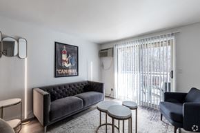 Wallingford apartment for rent - A living room with a black sofa, a grey armchair, a small table, and a framed picture on the wall.