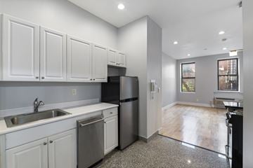 New York triplex for rent - A kitchen with white cabinets and a black refrigerator.