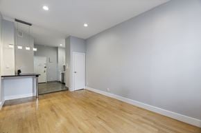 New York triplex for rent - A spacious room with wooden flooring and a large mirror on the wall.