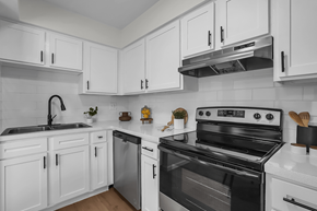 Columbus townhouse for rent - A black and white kitchen with white cabinets and a black stove top oven.