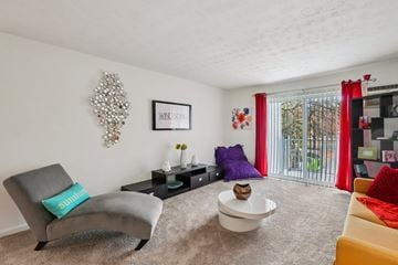 Pontiac apartment for rent - A living room with a grey chair and a white bowl on the carpet.