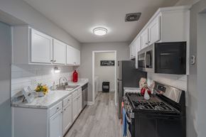 Pontiac apartment for rent - a kitchen with white cabinets and black appliances and a stove