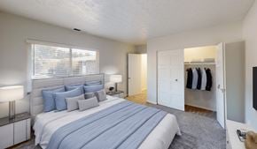 Columbus townhouse for rent - A bedroom with a large bed and a closet with clothes hanging.