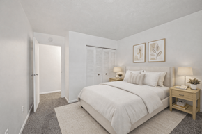 Lancaster townhouse for rent - A bedroom with a large bed, a nightstand, and a small table with a plant on it.