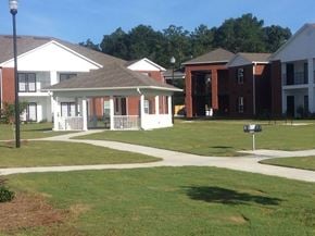 Andalusia apartment for rent - A white building with a porch is in the middle of a grassy area.
