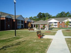 Cedartown apartment for rent - A grassy area with benches and a pathway in front of apartment buildings.