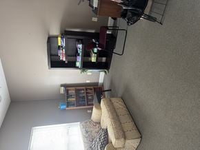 Jacksonville apartment for rent - A living room with a couch, a television, and a window with blinds.