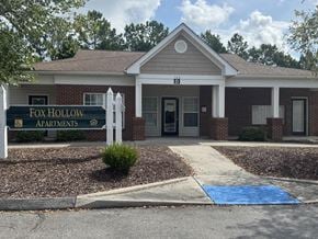 Jacksonville apartment for rent - The front of the Fox Hollow Apartments building is shown with a blue mat on the sidewalk.