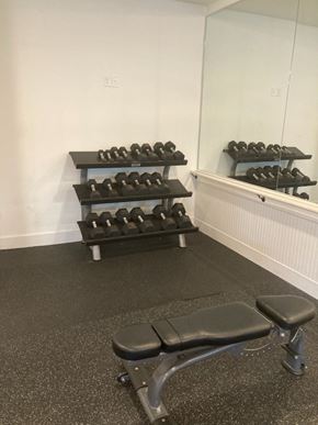 Atlanta apartment for rent - A gym room with a bench, weights and mirror.