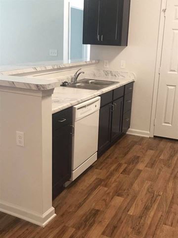 Wilson apartment for rent - A kitchen with black cabinets and white appliances.