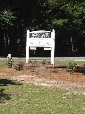 Ridgeland apartment for rent - A sign for Logan Lane Apartments stands in front of a wooded area.