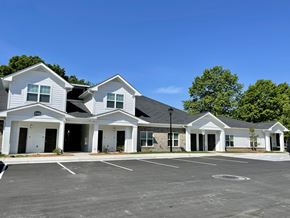 Charlotte apartment for rent - A row of white houses with a parking lot in front.