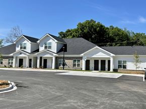 Charlotte apartment for rent - A large white building with a black roof and a parking lot in front.