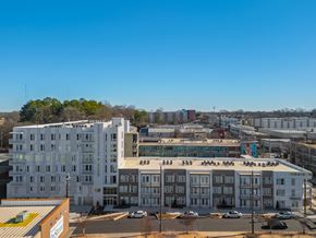 Atlanta apartment for rent - A large white building with a red roof is in the foreground of a city street.