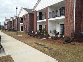 Monroeville apartment for rent - A row of red and white townhouses with a sidewalk in front.