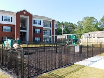 Ringgold apartment for rent - A playground with a black fence and a red brick building in the background.
