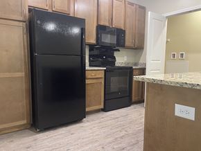 Buford apartment for rent - A black refrigerator is in a kitchen with wooden cabinets.