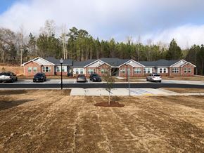 Winnsboro apartment for rent - A parking lot in front of a building with a tree in the middle.