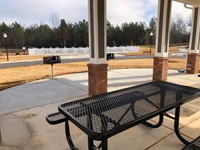 Winnsboro apartment for rent - A black metal table is in front of a white fence and a brick pillar.