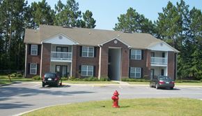 Jesup apartment for rent - A red fire hydrant is in front of a brick apartment building.