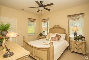 Newnan apartment for rent - A bedroom with a large bed, a dresser, and a ceiling fan.