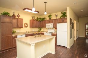 Newnan apartment for rent - A kitchen with brown cabinets and a white fridge.