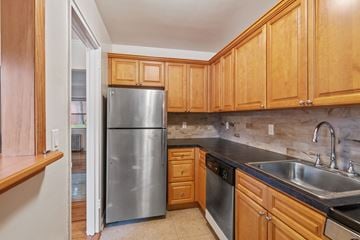 Fair Lawn triplex for rent - A kitchen with wooden cabinets and a stainless steel refrigerator.