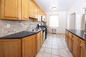 Millburn apartment for rent - A kitchen with wooden cabinets and black countertops.