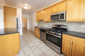 Millburn apartment for rent - A kitchen with wooden cabinets and a black countertop.