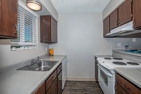 Spokane apartment for rent - a kitchen with white appliances and wooden cabinets and a sink at Lincoln Village Apartments, Spokane, 99208