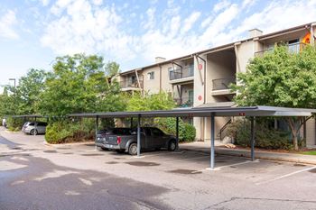 A parking lot with a car parked under awning in front of a building