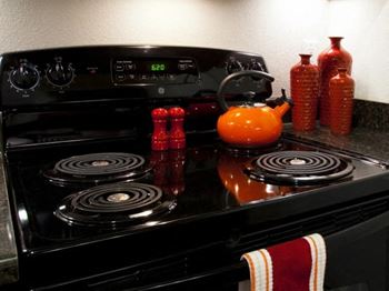 A black stove top oven sitting next to a orange teapot