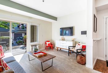 A living room with white walls and a sliding glass door that leads to a patio
