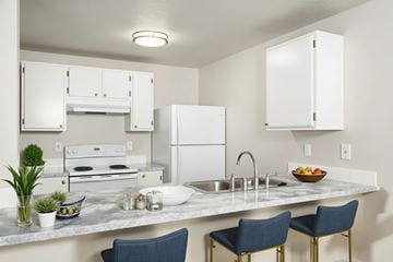 Coeur Dalene apartment for rent - A kitchen with a white refrigerator, a white oven, and a white countertop with a bowl of fruit on it.