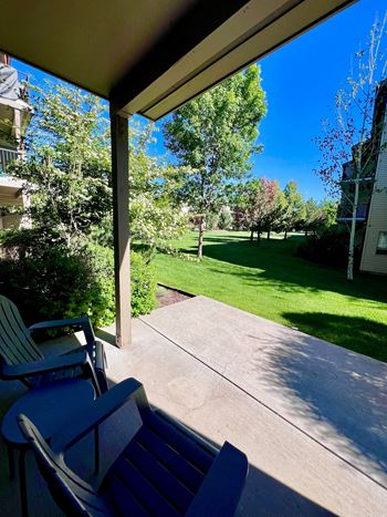 A patio with a table and chairs overlooks a green lawn.