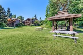 Spokane apartment for rent - a picnic table and gazebo in a grassy area with apartment buildings in the at Lincoln Village Apartments, Washington, 99208