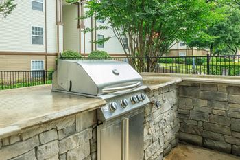 A stainless steel grill is on a stone patio.