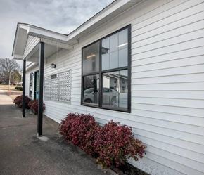 Athens apartment for rent - the side of a white building with windows and a sidewalk at Cleo Apartments, Athens, AL