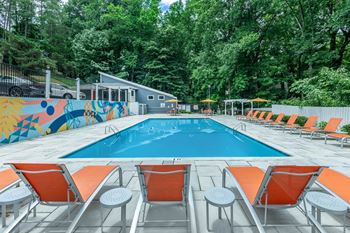 A pool surrounded by orange chairs and a mural.