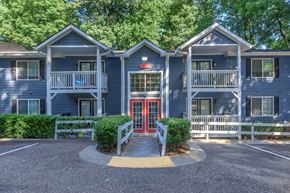 Marietta apartment for rent - A building with a red door and a white fence in front at Crest at East Cobb Apartments, Marietta, GA