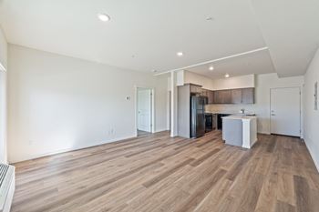 An empty living room and kitchen with wood flooring