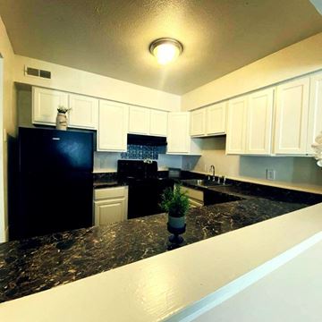 Greensboro apartment for rent - A black fridge and white cabinets in a kitchen.