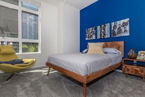 Tacoma apartment for rent - a bedroom with a blue accent wall and a bed with a wooden headboard at Napoleon Apartments, Tacoma, WA
