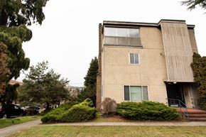 Seattle apartment for rent - A beige building with a green bush in front.